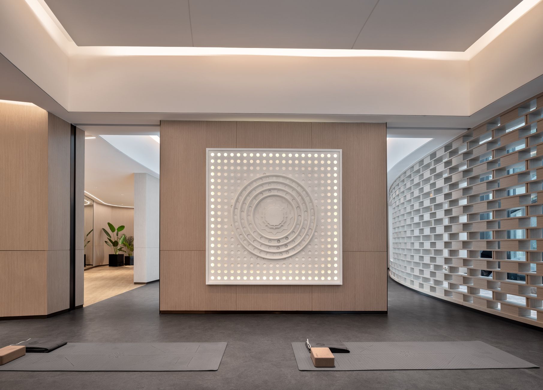 Spacious modern yoga studio interior featuring a striking wall art piece and yoga mats on wooden flooring.